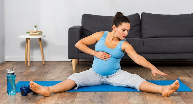 Vista frontale della donna incinta, formazione a casa sulla stuoia