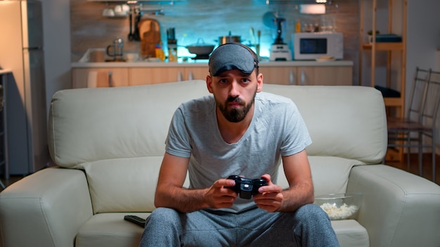 Front view of pro gamer sitting on sofa in front of television\
while playing videogames competition