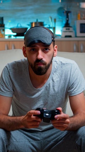 Front view of pro gamer sitting on sofa in front of television while playing videogames competition