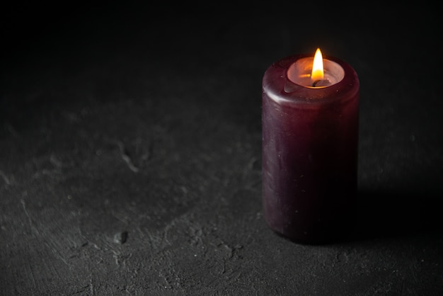 Front view of purple candle on dark