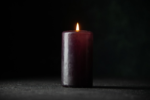 Front view of purple candle on dark