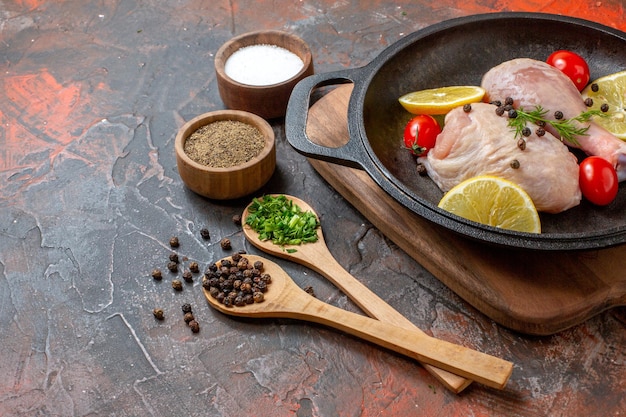 Front view raw chicken with lemon and cherry tomatoes inside pan on dark background cuisine food meat color meal dish vegetable