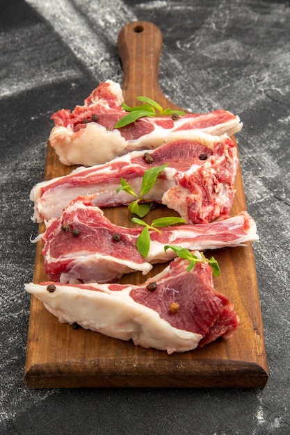 Vista frontale fette di carne cruda su sfondo grigio carne pollo insalata colore vegetale foto animale mucca