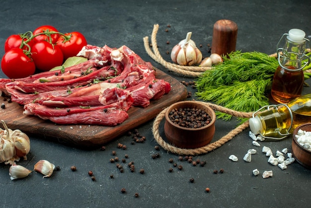 Вид спереди ломтики сырого мяса со свежими овощами и зеленью на темном фоне жарить мясник еда блюдо еда приготовление салата мясо