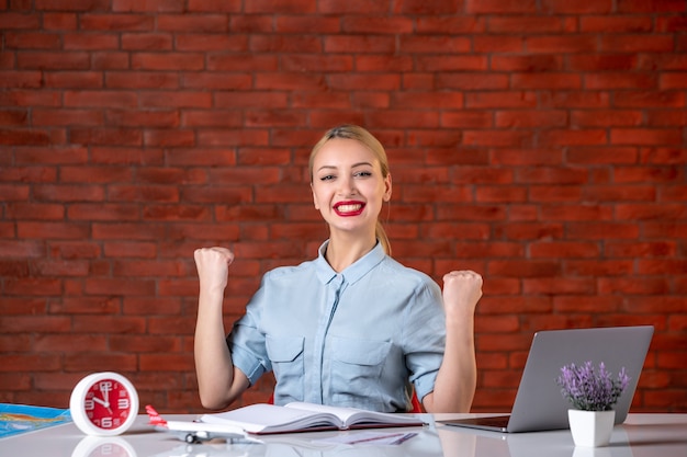 front view of rejoicing travel agent sitting behind her working place occupation global tourism manager service map agency assistant indoors