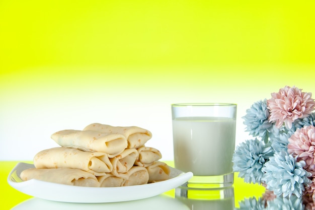 front view rolled sweet pancakes inside plate with glass of milk on yellow background meal cake morning food breakfast sugar color egg