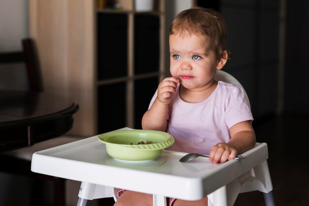 Front view of sad baby eating