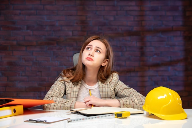 front view sad female engineer sitting behind her working place job agenda property corporate business contractor builder plan success