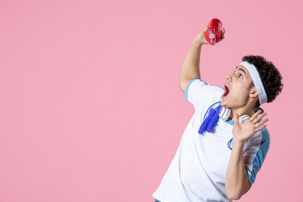 Front view scared male athlete in sport clothes with bottle of water looking above