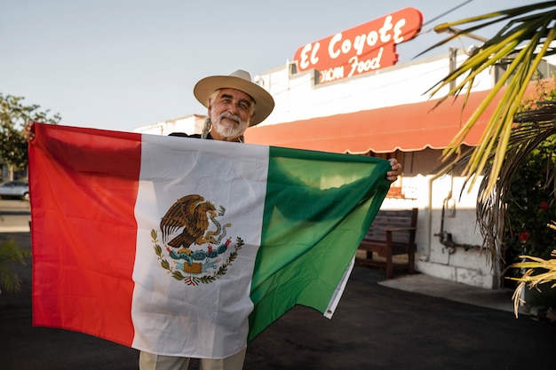 Photo front view senior man holding mexican flag