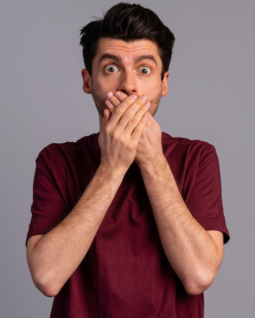 Photo front view of shocked man covering his mouth