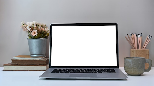 Front view of simple workspace with white blank screen monitor computer laptop and equipment on white desk.