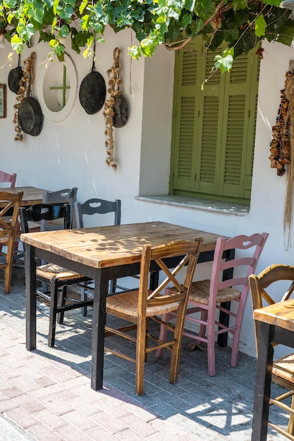 Front view of small cafe exterior Table and empty chairs outdoor near the white wall Tourist places Typical Mediterranean restaurant a place holidays in the summer Kos island Greece