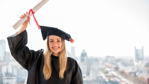 Foto ragazza sorridente di vista frontale che si laurea esaminando la macchina fotografica