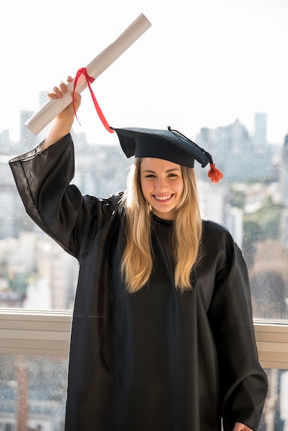 Foto laureato di smiley di vista frontale che sostiene certificato