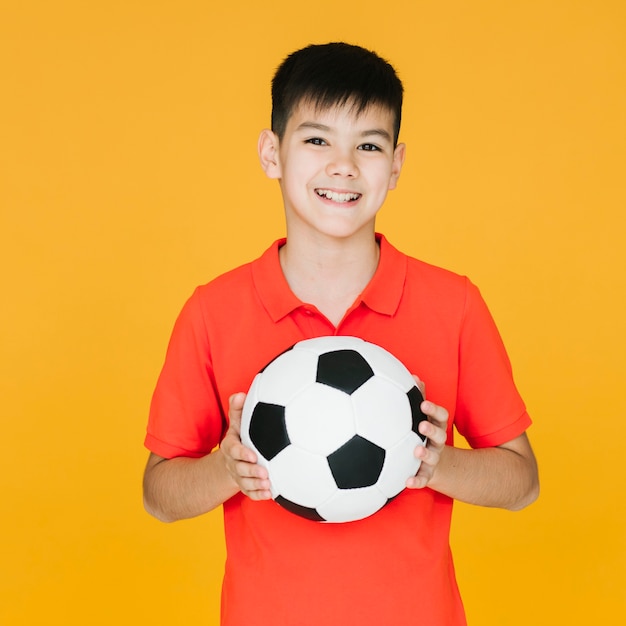 Фото Вид спереди смайлик ребенок держит футбольный мяч
