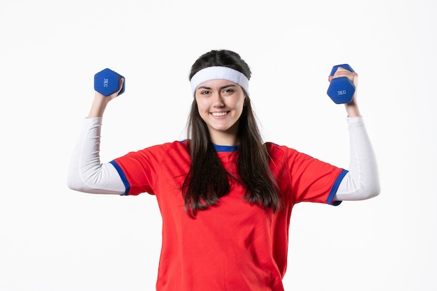 Giovane femmina sorridente di vista frontale in vestiti di sport che risolve con i dumbbells