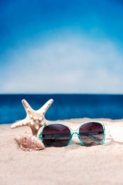 Foto vista frontale degli occhiali da sole e delle stelle marine sulla spiaggia