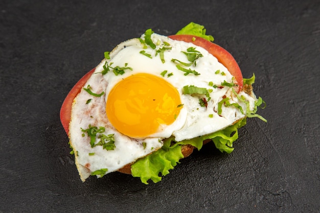 Vista frontale gustoso panino con uova e pomodori su sfondo scuro pasto uovo colazione pane pranzo cibo frittata bollire