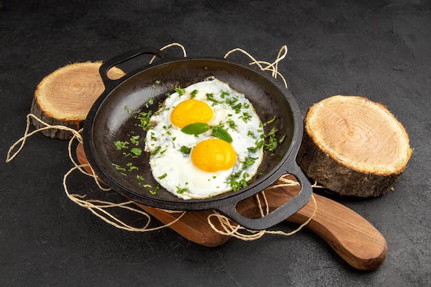 Photo front view tasty scrambled eggs with greens inside pan on dark background breakfast bread food meal morning omelette tea lunch