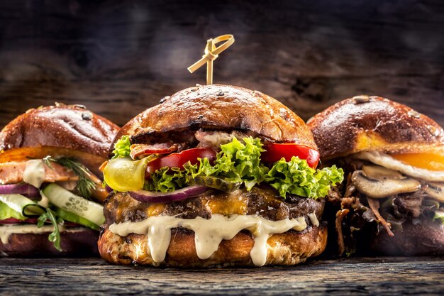 Front view on three large beef salmon and kebab burgers stuffed with fresh vegetable salad and dressing