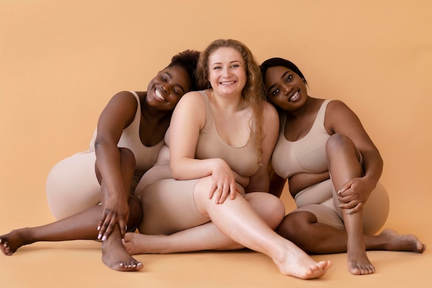 Photo front view of three smiley women in nude body shapers posing together