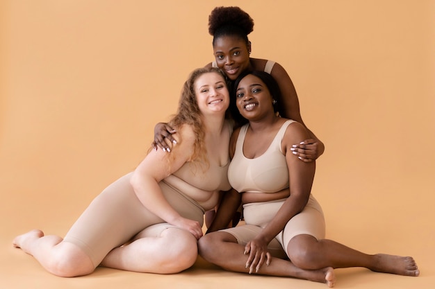 Front view of three women in nude illusion body shapers posing together