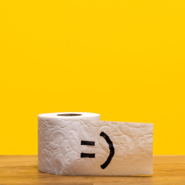 Front view of toilet paper roll with smiley face and copy space