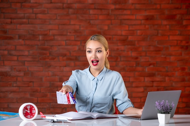 front view of travel agent sitting behind her working place and giving tickets global manager agency indoors tourism flight assistant map service