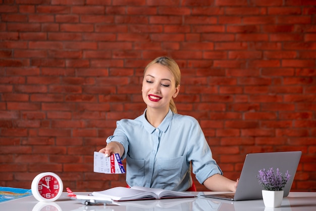 front view of travel agent sitting behind her working place and giving tickets global manager agency indoors tourism flight occupation map service