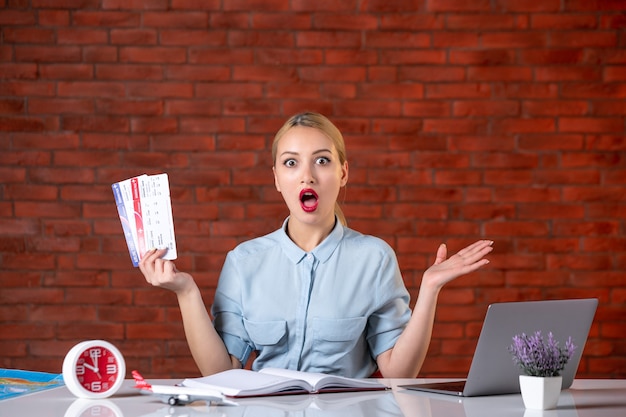 front view of travel agent sitting behind her working place with plane tickets global manager indoors service flight occupation assistant map agency