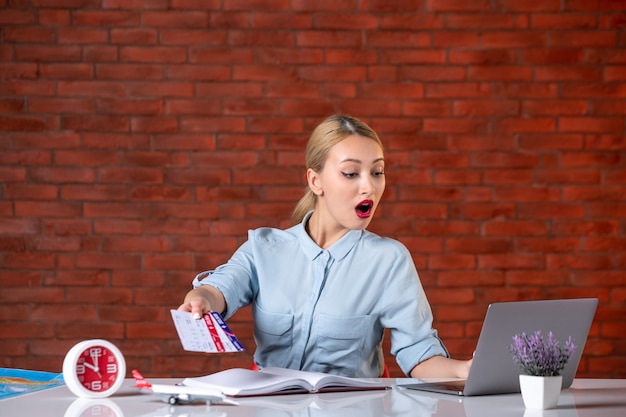 front view of travel agent sitting behind her working place with tickets global manager agency indoors tourism flight occupation assistant map service