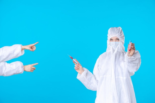 front view two female doctors in protective suit and mask one holding injection on the blue background medical covid- virus health science hospital pandemic