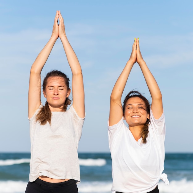 Vista frontale di due amiche di smiley che lavorano insieme sulla spiaggia