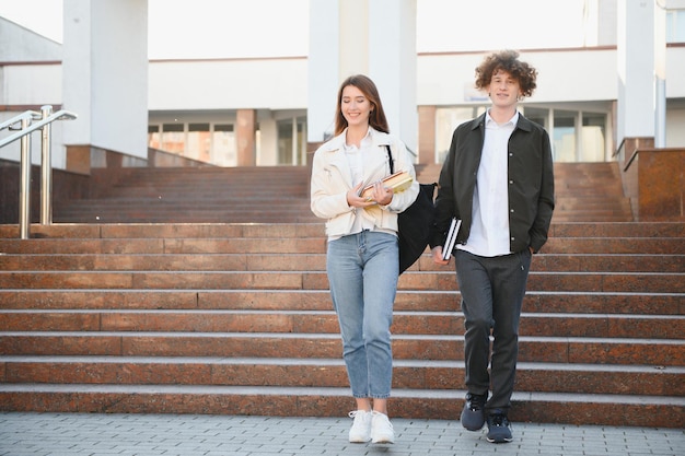 大学のキャンパスで歩いたり話したりする 2 人の学生の正面図