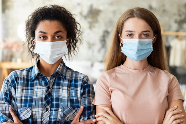 Front view of two women wearing medical masks at home