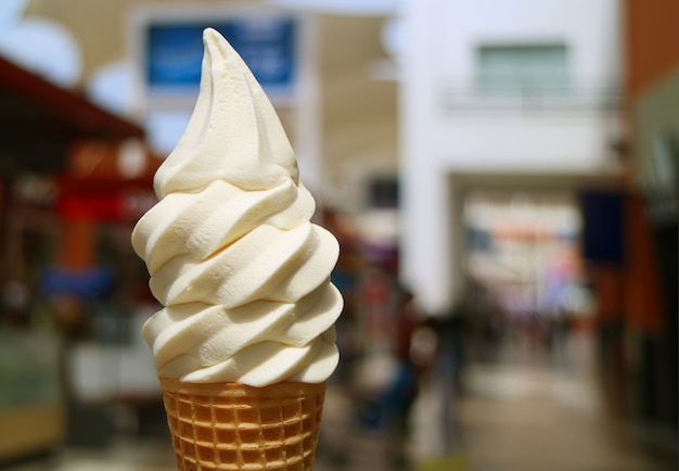 바닐라 우유 소프트의 전면보기는 배경에서 흐리게 시내 중심보기와 햇빛에 아이스크림 콘을 제공