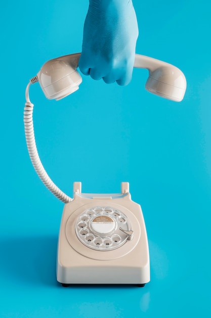 Photo front view of vintage telephone with hand in glove holding receiver