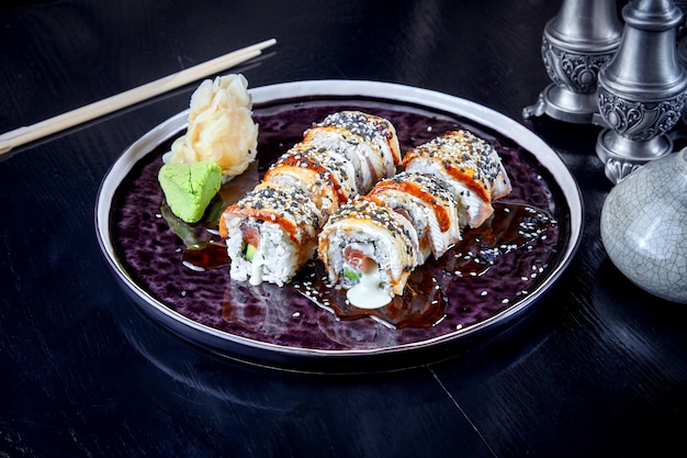 Front view on warm roll with tuna, eel and cream. Suchi. japanese food style. Seafood. Healthy, balanced, dieting meal. sushi rolls set on dark plate. Copy space, food background.