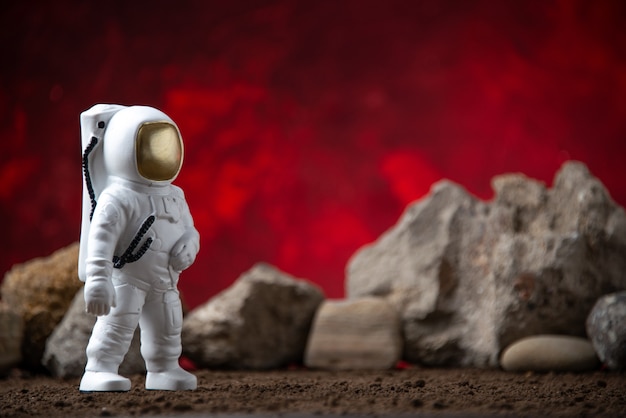 Вид спереди белого астронавта с камнями на красной космической фантастической луне