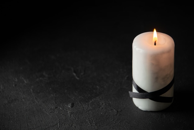 Front view of white candle on dark