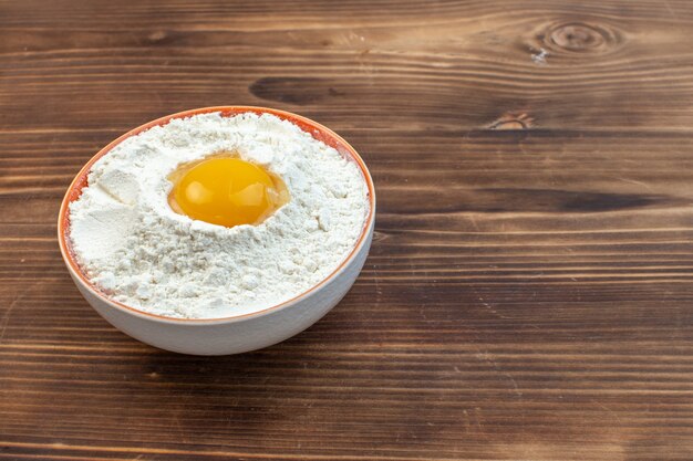 Photo front view white flour with egg inside plate on brown background cooking food pastry cuisine meat cake bread