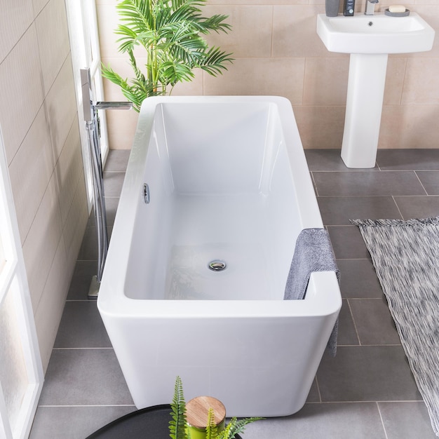 Front view of a white tub in bright bathroom with tiled floor and walls