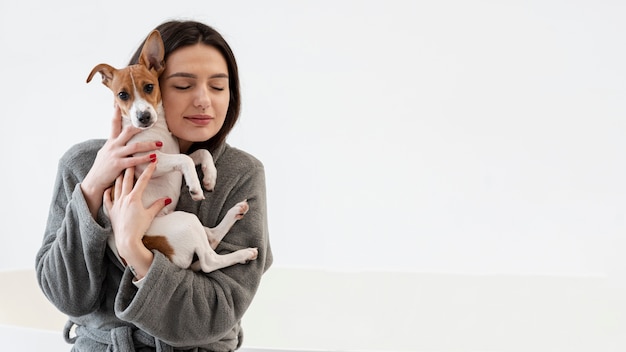 Photo front view of woman in bathrobe holding her dog