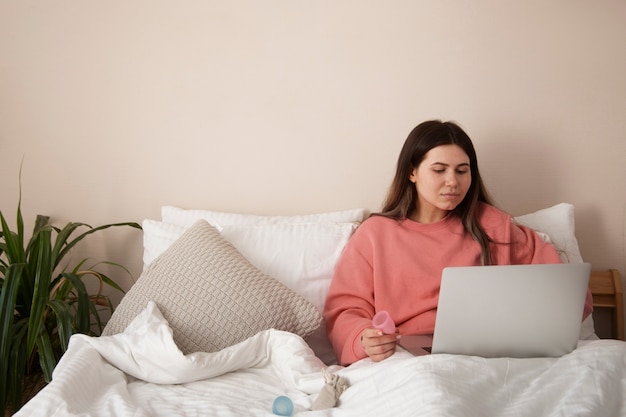 Front view woman in bed with laptop