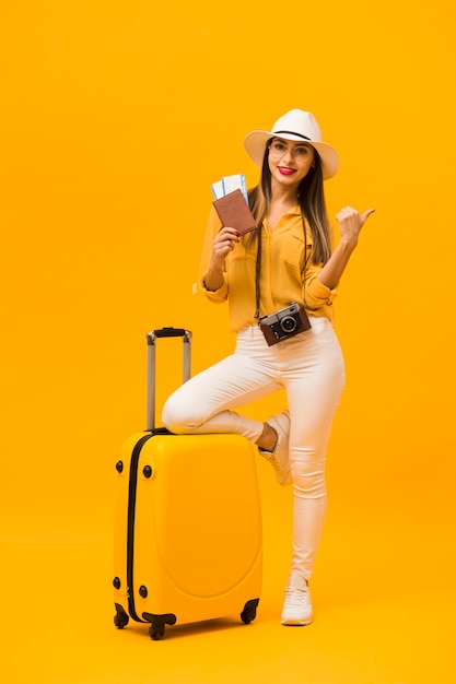 Foto vista frontale della donna che è pronta per la vacanza con i bagagli e gli elementi essenziali di viaggio