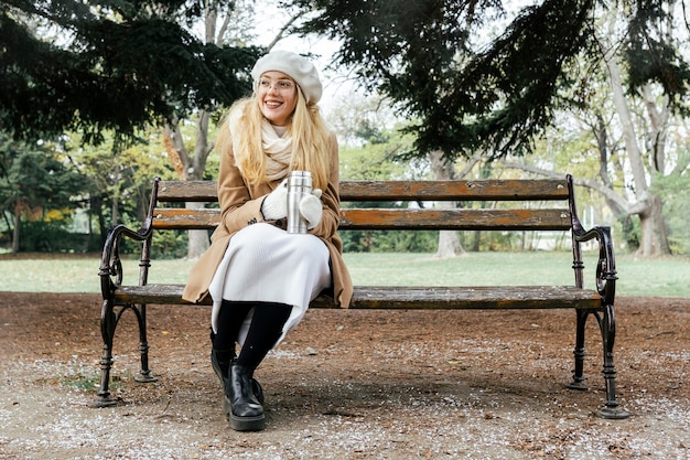 Vista frontale della donna sulla panchina nel parco durante l'inverno