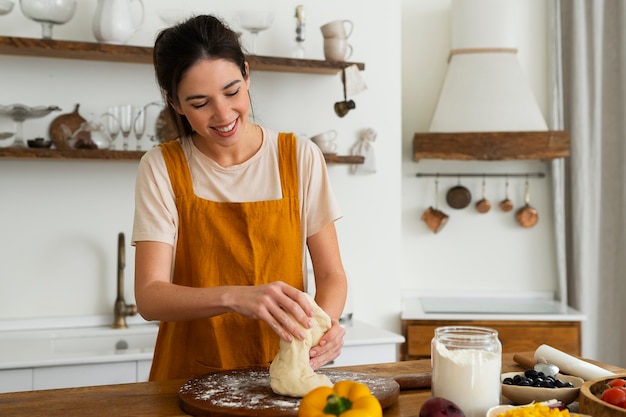 Foto donna di vista frontale che cucina pizza in cucina