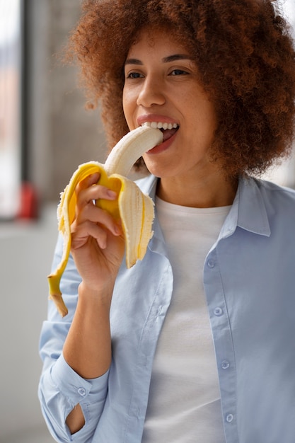 Foto donna di vista frontale che mangia banana