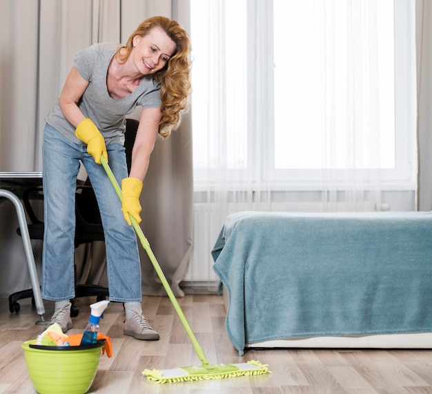Foto vista frontale della donna che pulisce felicemente il pavimento